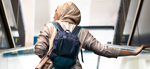 Muslimin auf einer Rolltreppe im Bahnhof